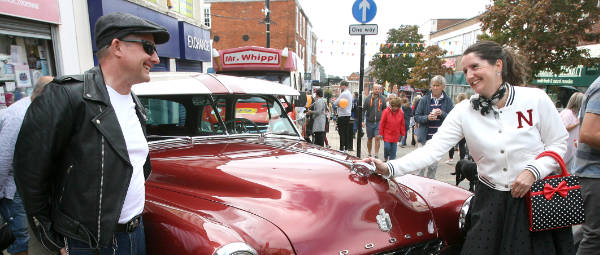 Banner photo of a lady in 1950's costume alongside a Chevy classic car at the Hinckley BID Motorshow